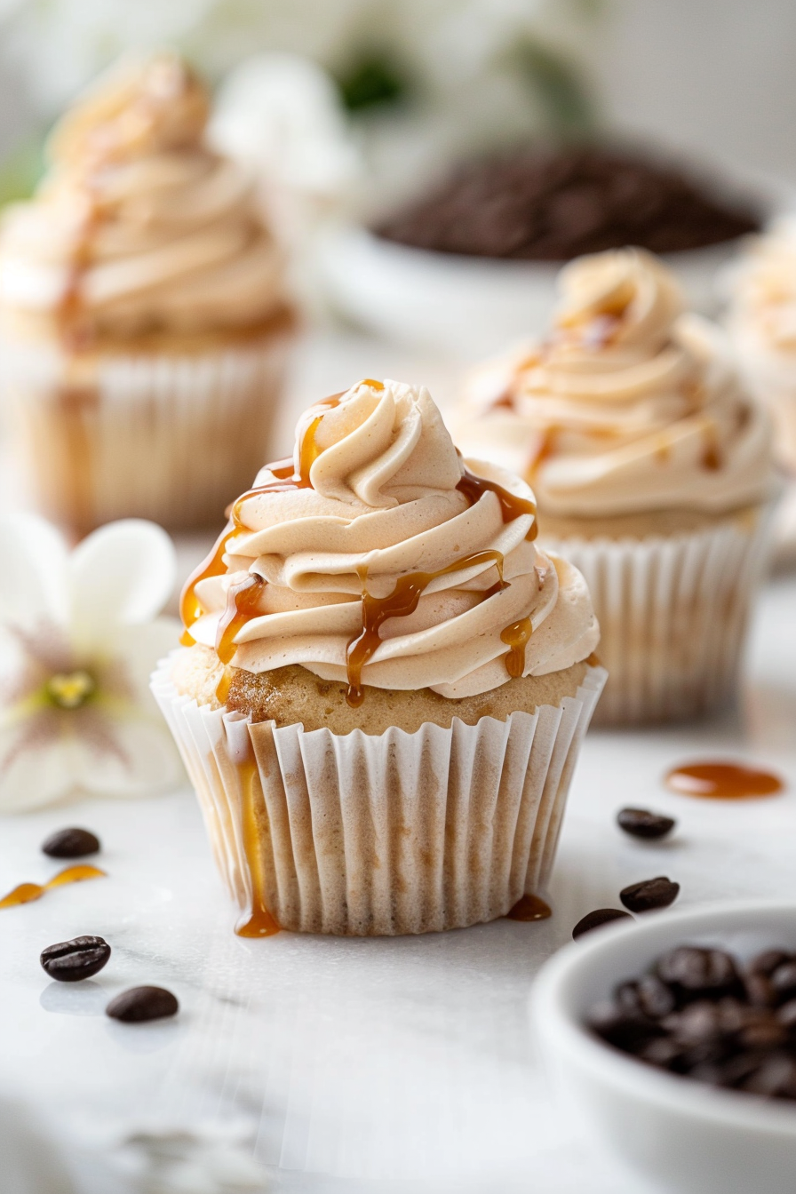 Caramel latte cupcakes with espresso-infused cake, topped with caramel buttercream and a glossy caramel drizzle on a marble surface